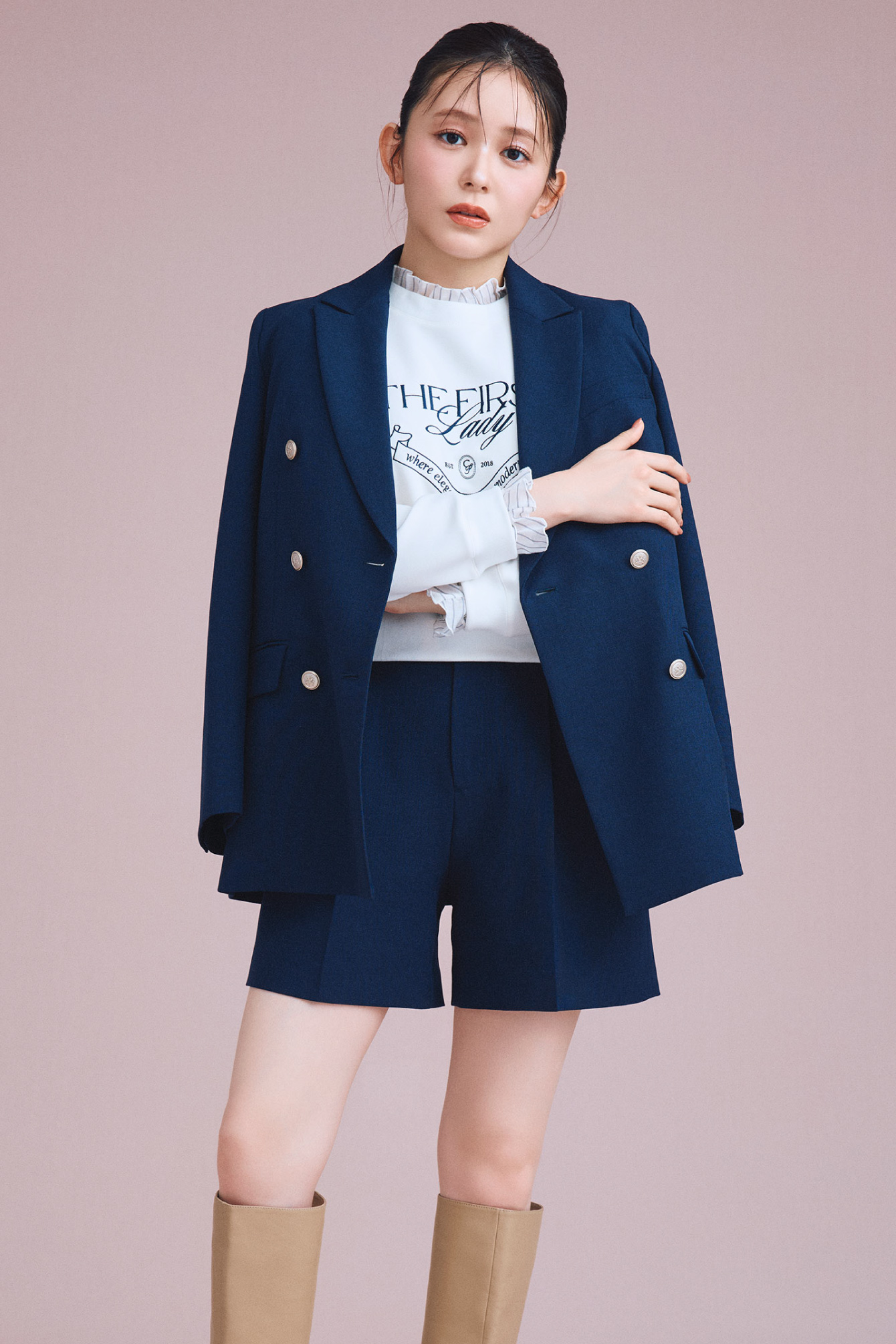 ダブルブレストテーラードジャケット、デタッチャブルスウェットトップス、ベルト付きショートパンツ、ロゴメタル付きロングブーツの着用イメージ