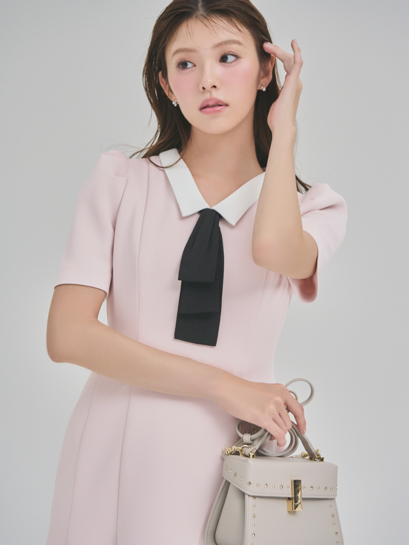 ピンク色の【WEB限定カラー】デタッチャブルポンチマーメイドワンピースと【リュタン】ビジュースタッズポシェットを着用した女性のイメージ